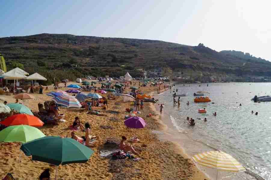 Familien genießen einen sonnigen Tag am Gnejna Bay, einem typischen Malta Sandstrand mit flach abfallendem Wasser.