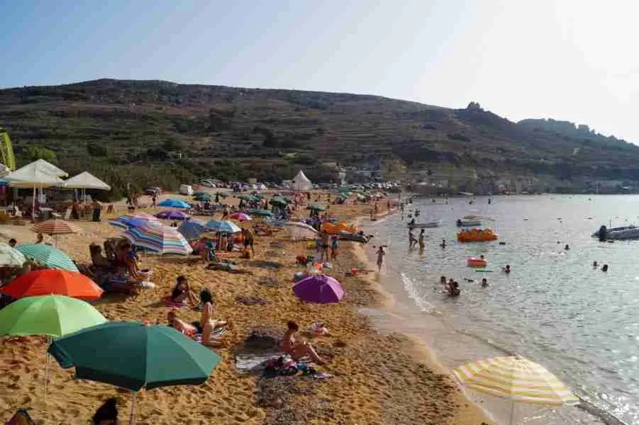 Familien genießen einen sonnigen Tag am Gnejna Bay, einem typischen Malta Sandstrand mit flach abfallendem Wasser.