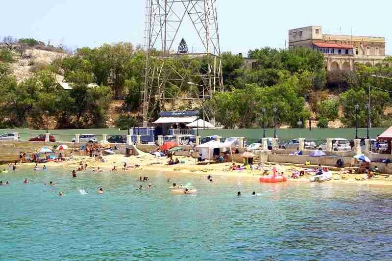 Einheimische entspannen auf Luftmatratzen im ruhigen Wasser der Rinella Bay, einem der schönsten Strände auf Malta.