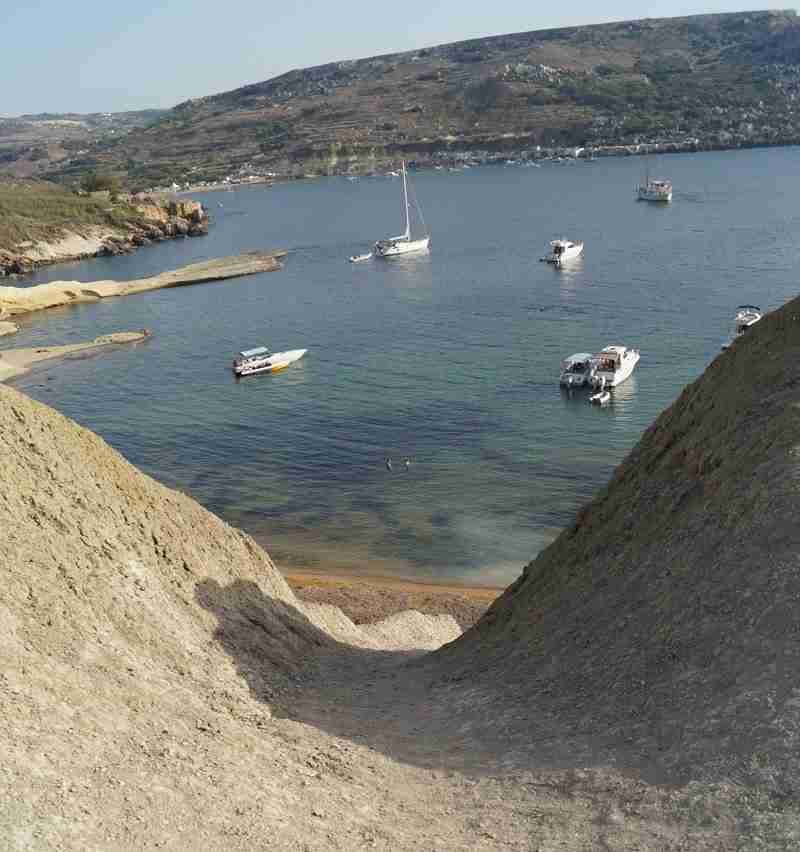 Der steile Pfad hinab zur Secret Ghajn Tuffieha Bay, einem der schönsten Strände auf Malta, eingebettet in die wilde Küstenlandschaft.