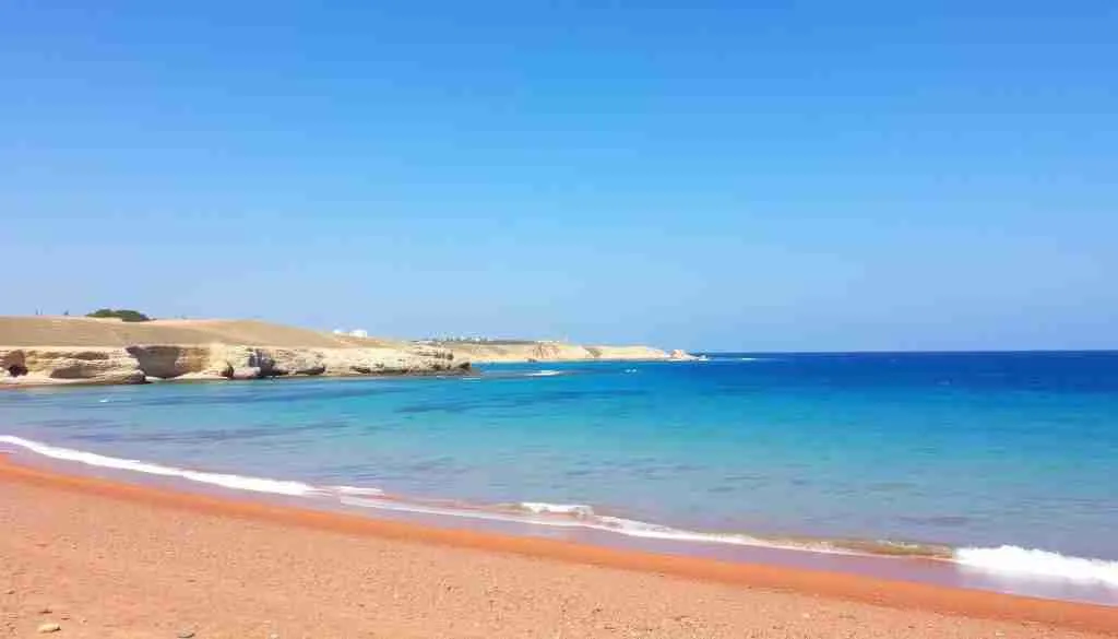 Ein Bild von der Ramla Bay auf Gozo, mit rötlichem Sandstrand und türkisfarbenem Wasser.
